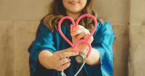 Nurse holding a stethoscope shaped like a heart, for a guide to surrogate medical screening