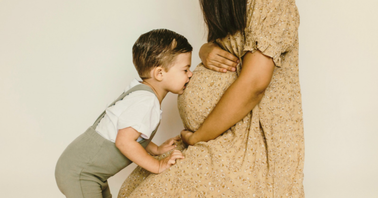 Little boy kissing his mom’s pregnant belly, illustrating surrogate requirements in Hawaii